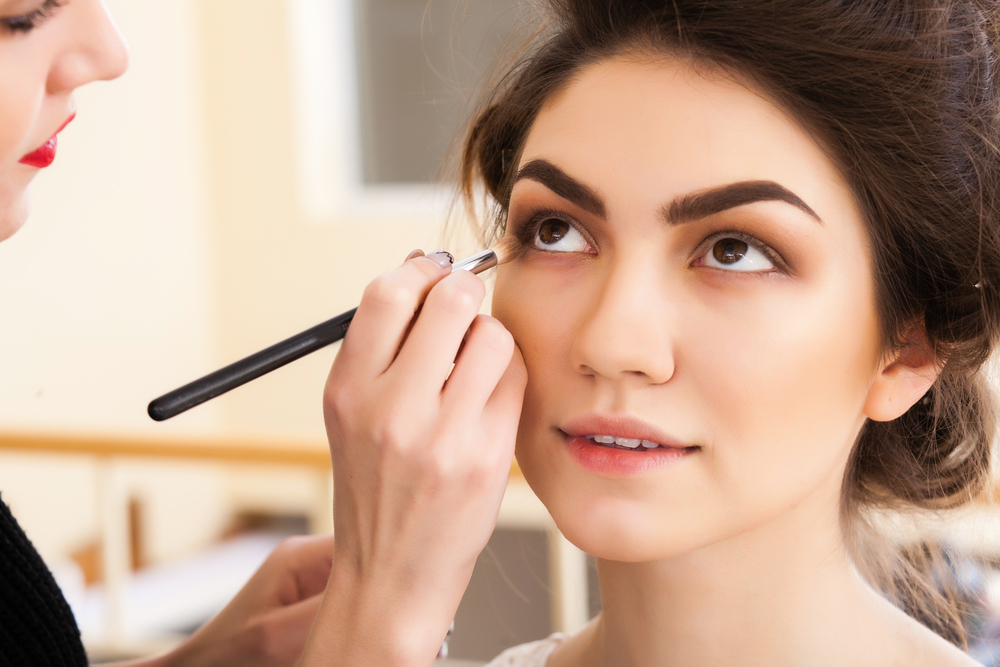 Makeup artist applies eye makeup to a brunette client.